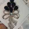 Crystal bow hijab brooch with navy teardrop stones above a rhinestone bow, gold tone